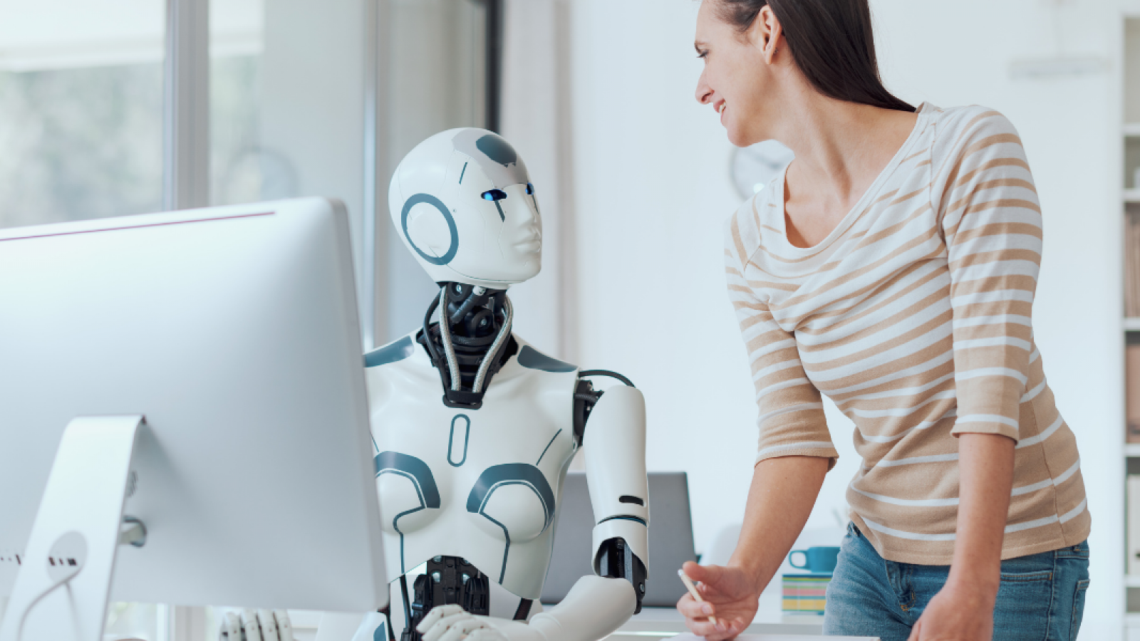 AI Roboter sitzt mit einer Frau am PC